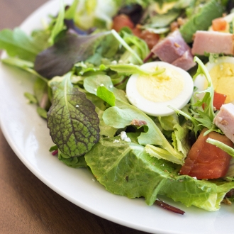 Salad on a plate with mixed greens, eggs and ham 