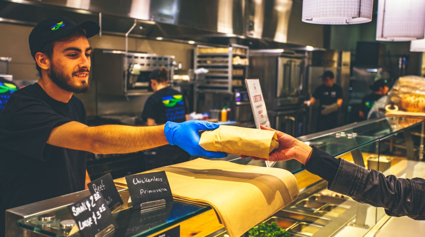 Employee handing sandwich to customer 