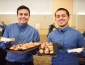 Two students holding catering trays of food 