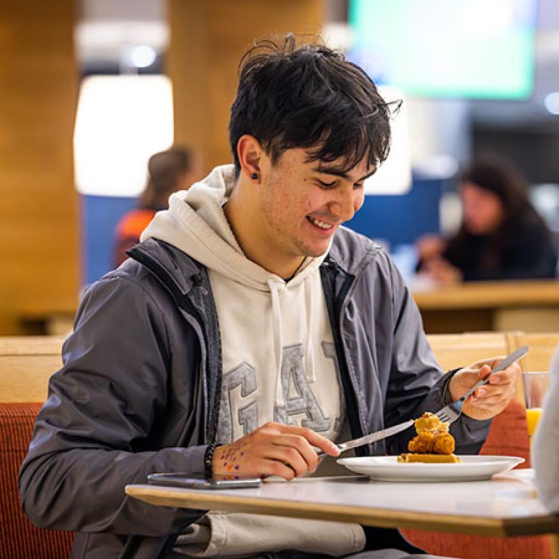 student eating at high top table in Kitchen