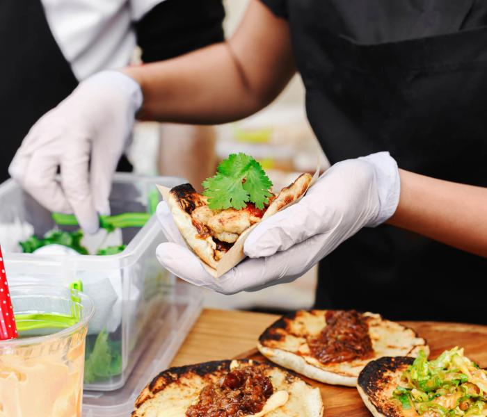 Hands wearing gloves preparing tacos