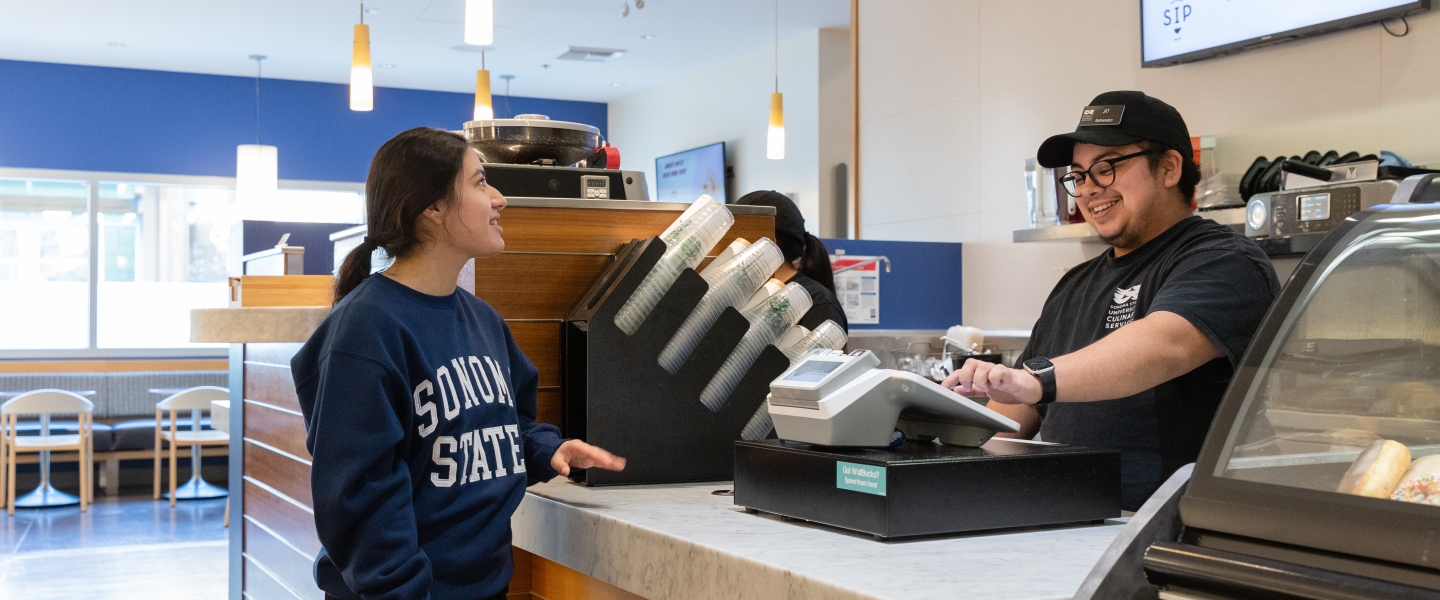 Student standing and ordering at Sip dining venue with cashier