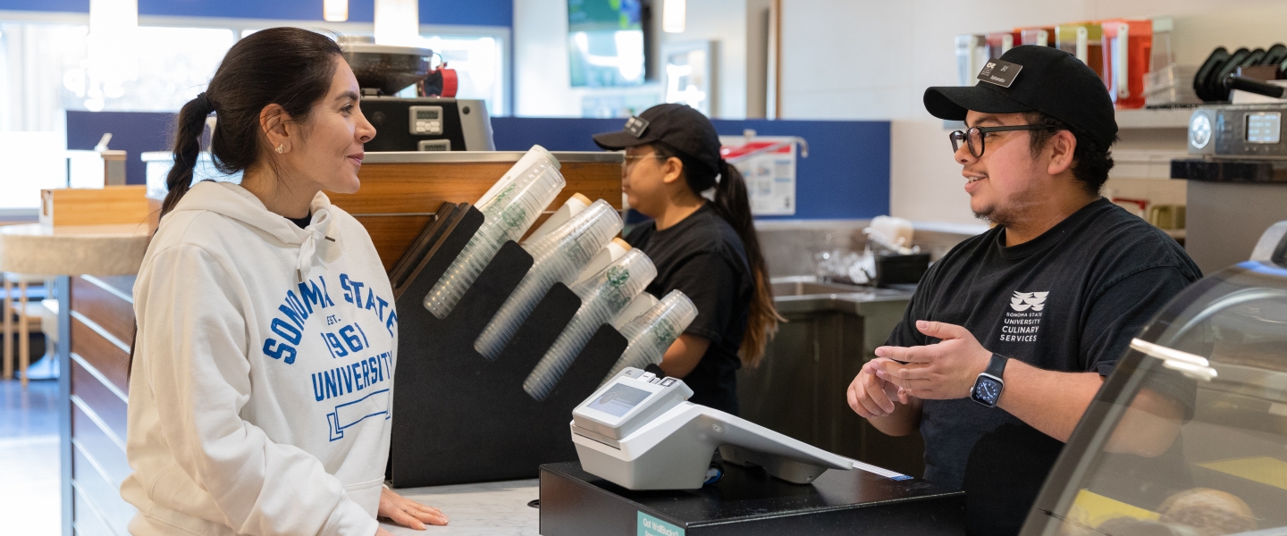 Student standing and ordering with cashier at register 