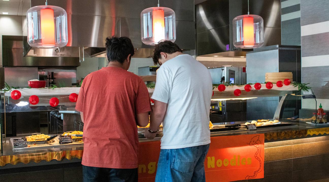 two students getting food at event