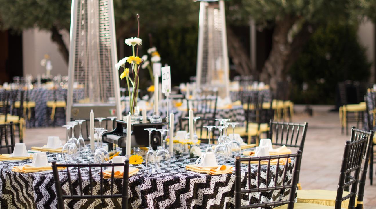 Event table setup with glassware and string lights above tables 