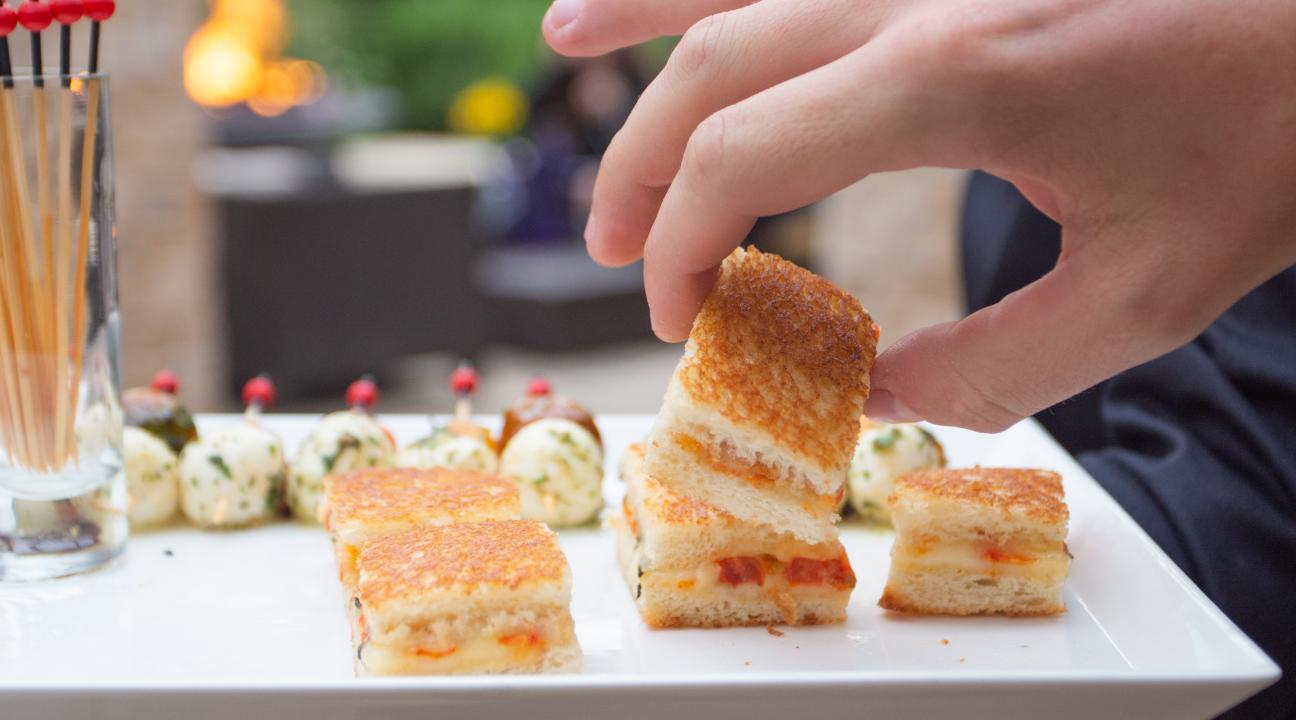 Hanf grabbing a mini sandwich on a plate 