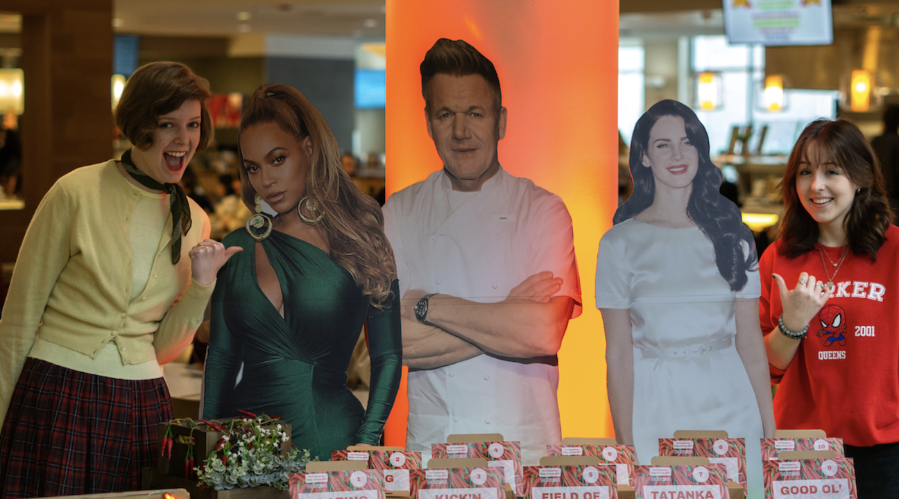 two students posing near the voting area with cut outs of Beyonce, Gordon Ramsay, and Lana Del Rey