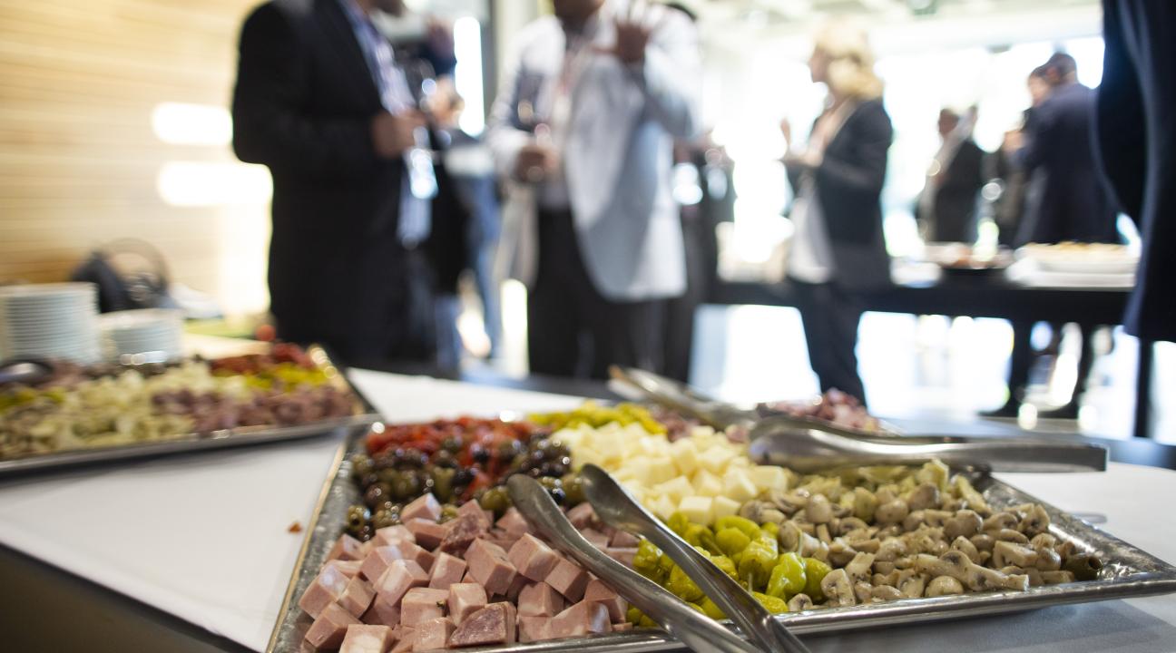 Catering tray of meats and cheese with guests in background 