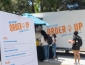 People standing in line to pick up food with a white food truck behind them