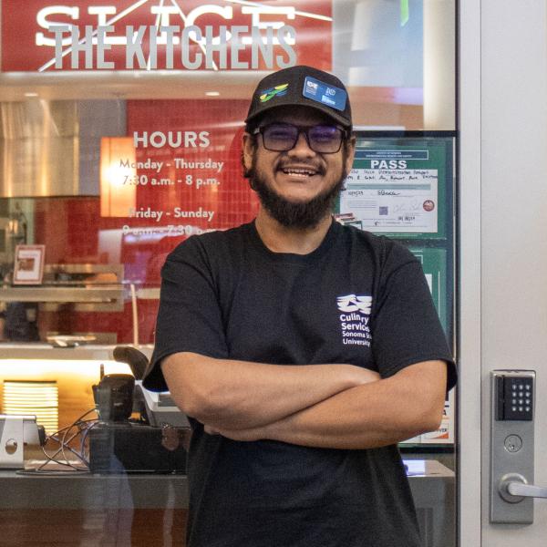 Student standing in front of the front door to the kitchens