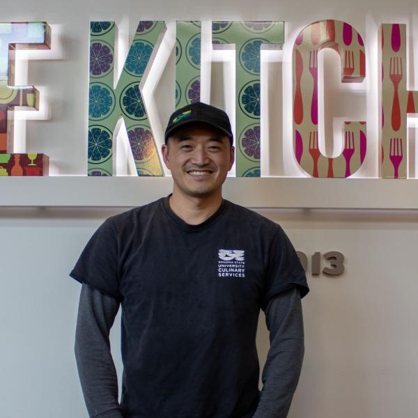 Student standing in front of the Kitchens sign