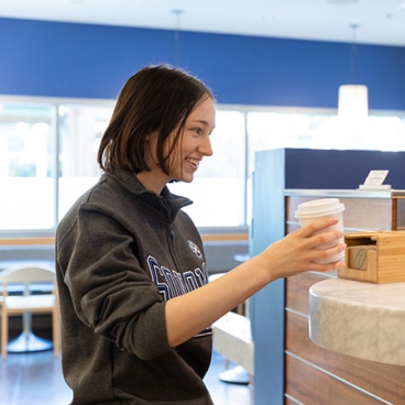 student holding a cup of coffee and smiling