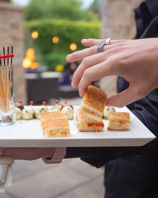 Hanf grabbing a mini sandwich on a plate 