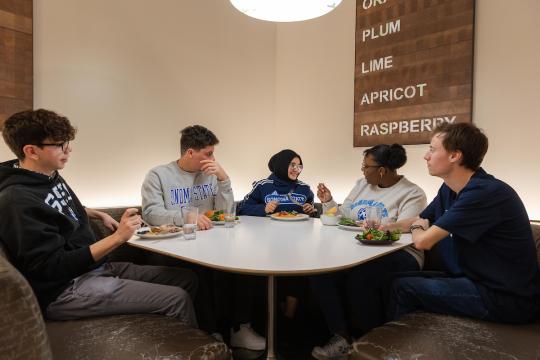 a group of students sitting around a table in the kitchens