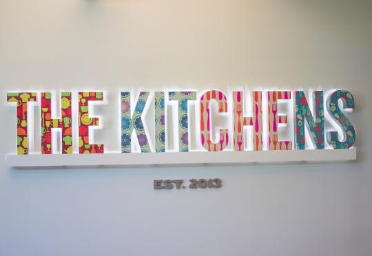 Brightly colored and patterned sign that says The Kitchens