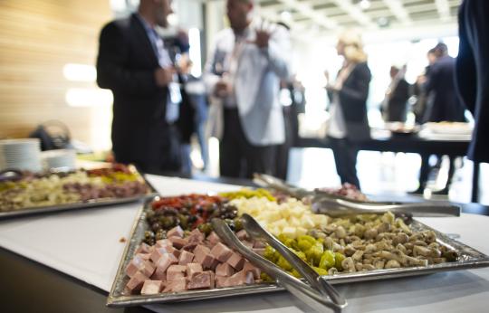 Catering tray of meats and cheese with guests in background 