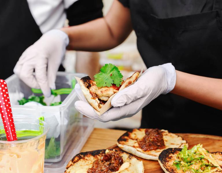 Hands wearing gloves preparing tacos
