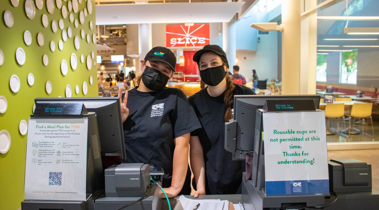 Two culinary employees standing behind registers