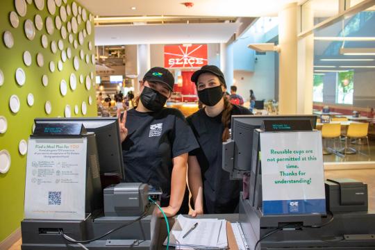 Two culinary employees standing behind registers